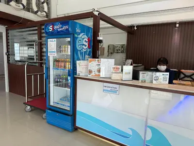 a woman wearing a face mask sitting at a store with a soda machine at Bed By Cruise Hotel At Samakkhi-Tivanont in Nonthaburi