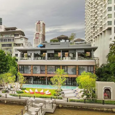 a building with a swimming pool next to a river at Ten Six Hundred, Chao Phraya, Bangkok by Preference, managed by The Ascott Limited in Bangkok