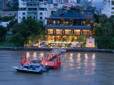 a boat is docked in a river next to a building at Ten Six Hundred, Chao Phraya, Bangkok by Preference, managed by The Ascott Limited in Bangkok