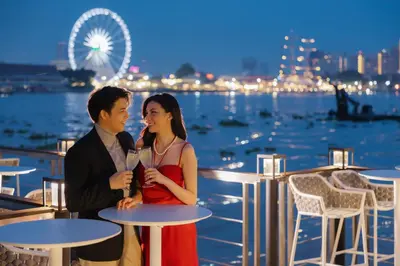 a man and a woman sitting at tables with drinks at Ten Six Hundred, Chao Phraya, Bangkok by Preference, managed by The Ascott Limited in Bangkok