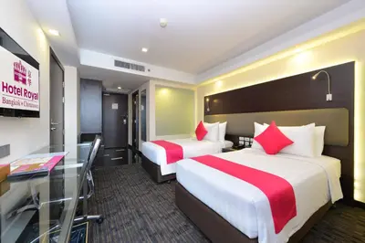 a hotel room with two beds and a desk at Hotel Royal Bangkok in Bangkok