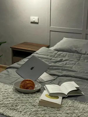 a laptop computer on a bed with a plate of bread and a book at AndStay in Bangkok