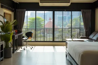 a bedroom with a bed and a balcony with a view at NORN Riverside Bangkok Hotel - นอนริมน้ำ in Bangkok