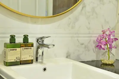 a bathroom sink with a bottle of soap and a mirror at NORN Riverside Bangkok Hotel - นอนริมน้ำ in Bangkok