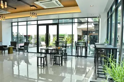 a lobby with chairs and tables in a building at NORN Riverside Bangkok Hotel - นอนริมน้ำ in Bangkok