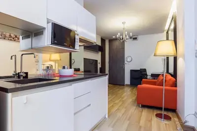 a kitchen with white cabinets and a red couch at Vinn condo in Amphoe Phra Khanong