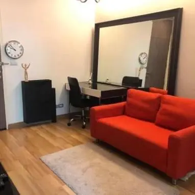 a living room with a red couch and a mirror at Vinn condo in Amphoe Phra Khanong