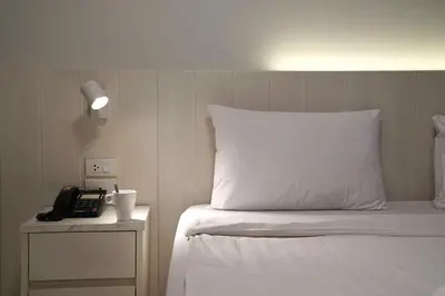 a bed with a white pillow and a telephone at View Place Hotel & Residence Lat Phrao 130 in Bangkok