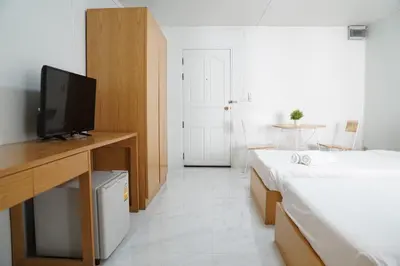 a room with two beds and a desk with a television at View Place Hotel & Residence Lat Phrao 130 in Bangkok