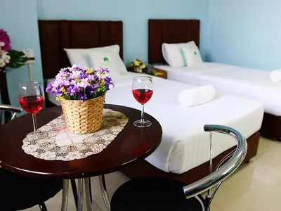 two glasses of wine and flowers on a table in a hotel room at Happyland Mansion in Bangkok