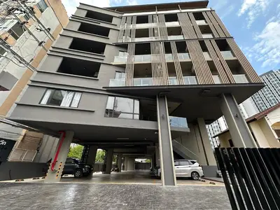 a tall apartment building with a parking lot at D Night Suite Hotel in Bangkok