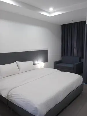 a bedroom with a large white bed and a chair at D Night Suite Hotel in Bangkok