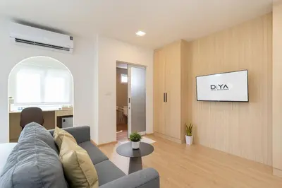 a living room with a couch and a tv on a wall at Diya Hotel Bangkok in Amphoe Phra Khanong