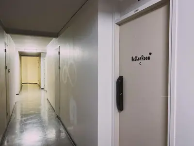 a hallway with white walls and a door with a sign on it at Better Room ห้องพักรายวัน เมืองทองธานี C5 in Nonthaburi