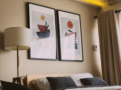 two framed pictures on a wall above a bed at Better Room ห้องพักรายวัน เมืองทองธานี C5 in Nonthaburi