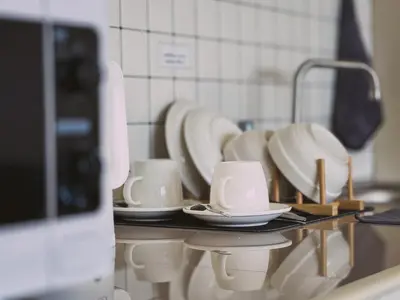 a row of white cups and saucers on a counter at Better Room ห้องพักรายวัน เมืองทองธานี C5 in Nonthaburi