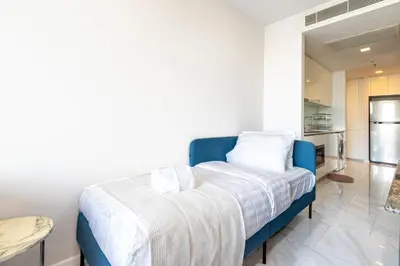 a bedroom with a blue bed and a kitchen at Hyde Sukhumvit 11 Branded Suites in Bangkok