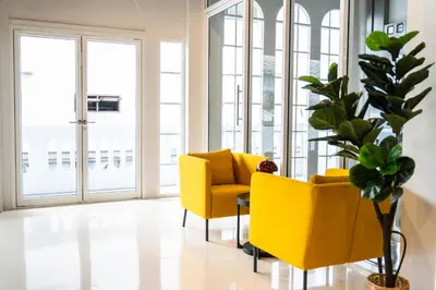 a living room with two yellow chairs and a potted plant at PIER 808 Hostel in Bangkok