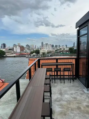 a deck with tables and chairs and a view of a city at PIER 808 Hostel in Bangkok