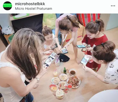 a group of girls standing around a table eating food at Micro Hostel in Bangkok