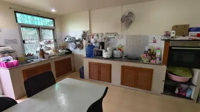 a kitchen with a table and a counter top at ธิติกาญจน์ อพาร์ทเม้นท์ in Ban Khlong Samrong