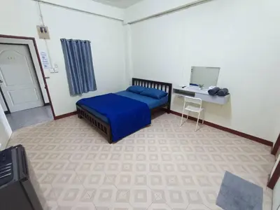 a bedroom with a blue bed and a desk at ธิติกาญจน์ อพาร์ทเม้นท์ in Ban Khlong Samrong