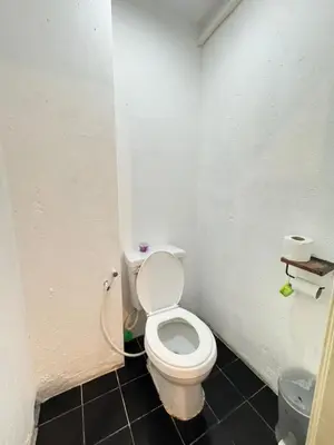 a bathroom with a white toilet in a room at Comfy Crib Hostel in Bangkok