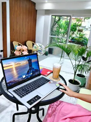 a person sitting at a table with a laptop computer at homey stay and cafe by hematoa in Bangkok