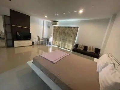 a bedroom with a large bed and a living room at BKK TEAK Hostel in Amphoe Phra Khanong