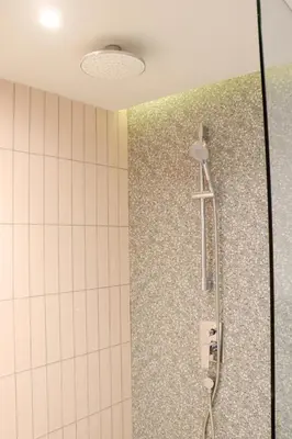 a shower in a bathroom with a tile wall at The Quarter Ratchathewi by UHG in Bangkok