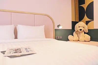a stuffed teddy bear sitting on a bed with a newspaper at The Quarter Ratchathewi by UHG in Bangkok