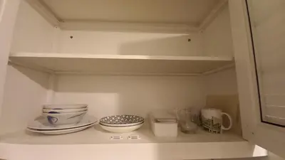 a cupboard with plates and bowls on a shelf at Silom Cityview Paradise Room in Bang Rak