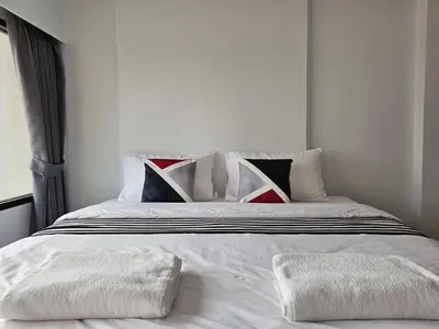 a white bed with two white towels on it at โรงแรมแอเรียเพลส สาทร (AREA Place) in Chong Nonsi
