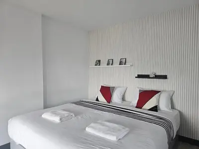 a white bedroom with a large bed with two pillows at โรงแรมแอเรียเพลส สาทร (AREA Place) in Chong Nonsi