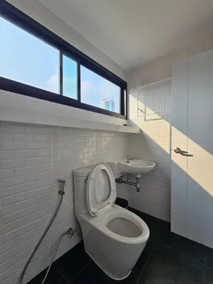 a bathroom with a toilet and a sink and a window at โรงแรมแอเรียเพลส สาทร (AREA Place) in Chong Nonsi