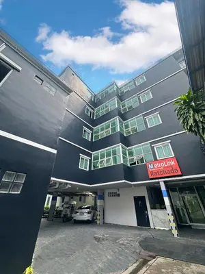 a building with a parking lot in front of it at Metro Link Ratchada Hotel in Bangkok