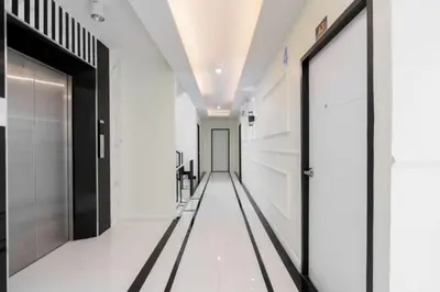 a hallway with black doors and white floors at Metro Link Ratchada Hotel in Bangkok