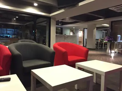 a waiting room with red chairs and tables at Metro Link Ratchada Hotel in Bangkok