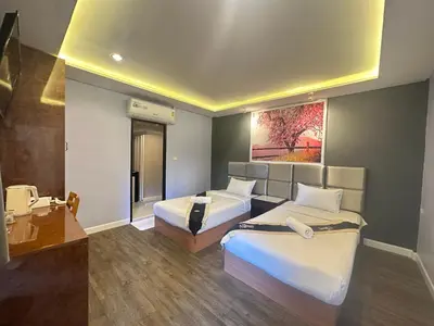 a hotel room with two beds and a desk at Metro Link Ratchada Hotel in Bangkok
