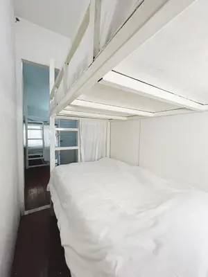 a white bed in a room with a bunk bed at Rotinis Hostel in Pom Prap