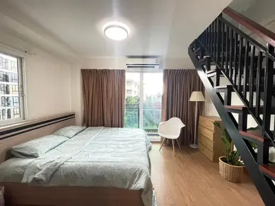 a bedroom with a bed and a spiral staircase at Modern 5-Bedroom Townhome near MRT and Local Charm in Bangkok