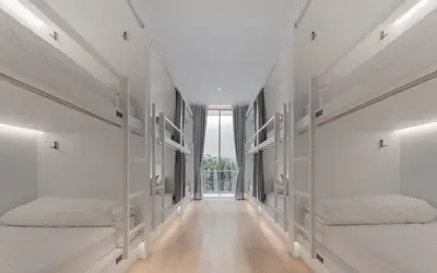 two beds in a room with white walls at Matini Hostel grandstation in Bangkok