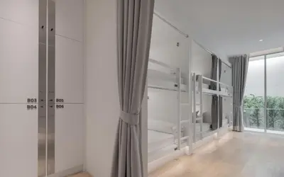 a room with white walls and a large window at Matini Hostel grandstation in Bangkok