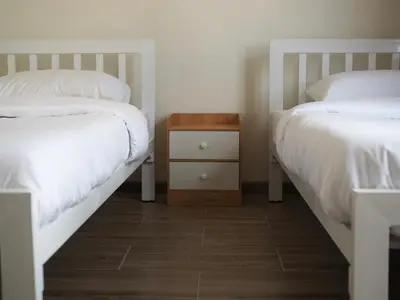 a bedroom with two beds and a nightstand between them at Krung Tone Hostel in Bangkok