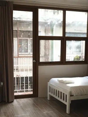 a bedroom with a bed and a large window at Krung Tone Hostel in Bangkok