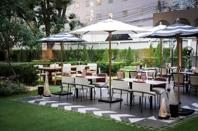 a patio with tables and chairs and umbrellas at Floral Court Hotel & Residence Sukhumvit 13 in Bangkok