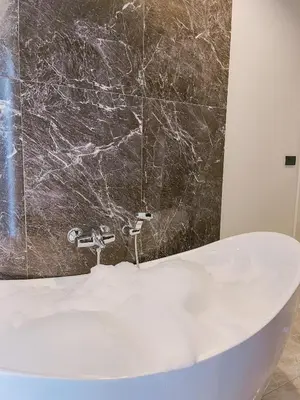 a bathroom with a white tub and a marble wall at KVILLA in Ban Khlong Bang Chak