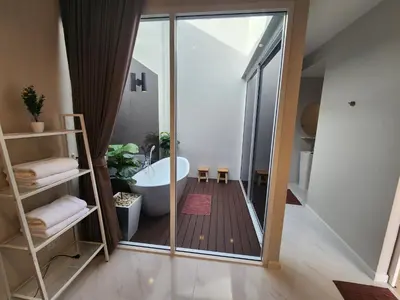 a bathroom with a tub and a glass door at KVILLA in Ban Khlong Bang Chak