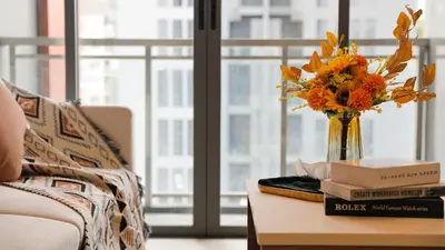 a vase of flowers on a table with books at Funstay Bangkok Circle Condo in Bangkok