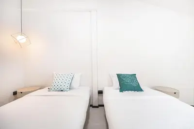 two beds in a room with white walls at The Mellow at Ekkamai in Bangkok